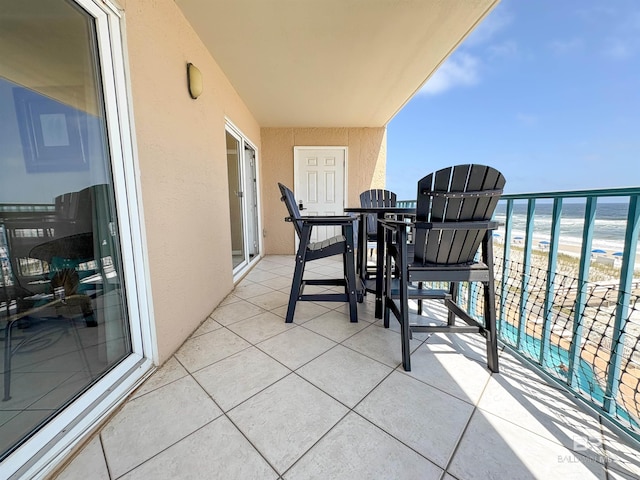 balcony with a view of the beach, outdoor dining space, and a water view