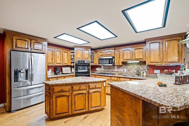 kitchen featuring a kitchen island, stainless steel appliances, light stone countertops, and light hardwood / wood-style floors