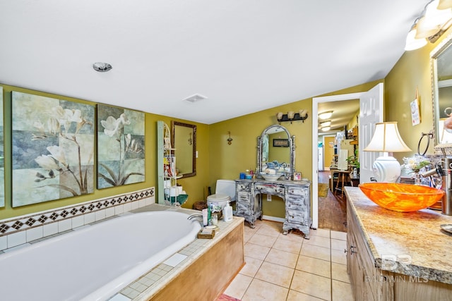 bathroom with tile patterned flooring, vanity, toilet, and a relaxing tiled tub