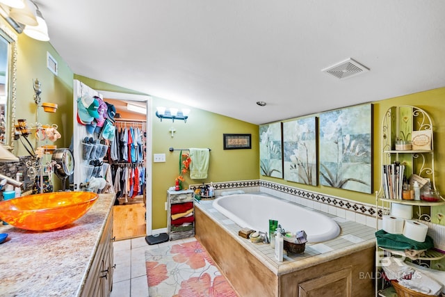 bathroom featuring tile patterned flooring, a tub to relax in, vaulted ceiling, and vanity