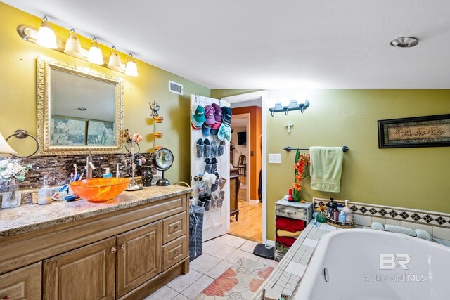 bathroom with lofted ceiling, vanity, a bathtub, and tile patterned floors