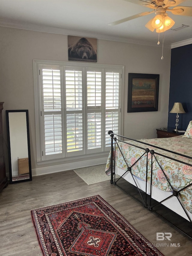 bedroom featuring hardwood / wood-style floors, multiple windows, ornamental molding, and ceiling fan