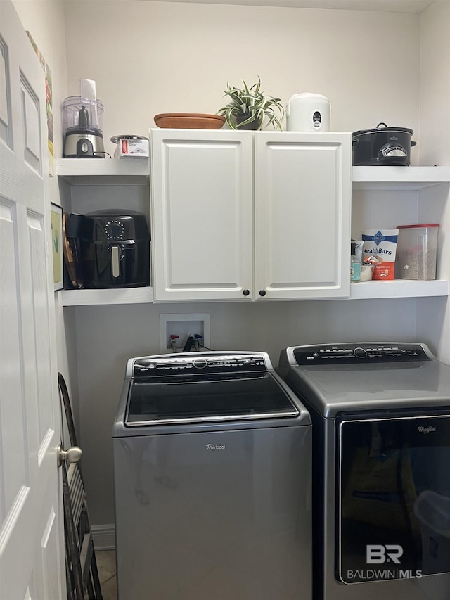 laundry room with washing machine and dryer, tile patterned flooring, and cabinets