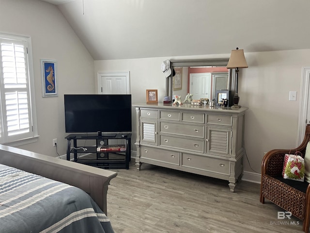 bedroom featuring multiple windows, light hardwood / wood-style floors, and vaulted ceiling