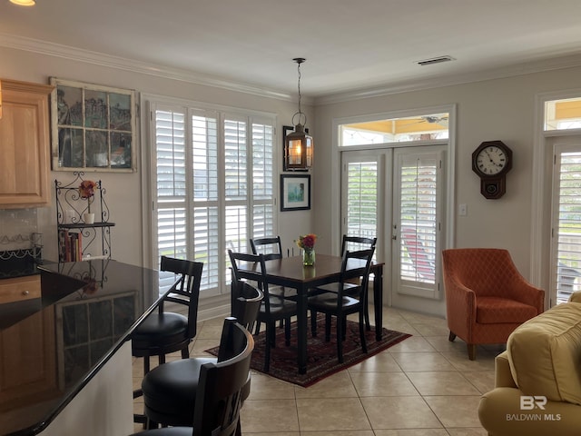 dining room with light tile patterned floors, ornamental molding, a wealth of natural light, and french doors