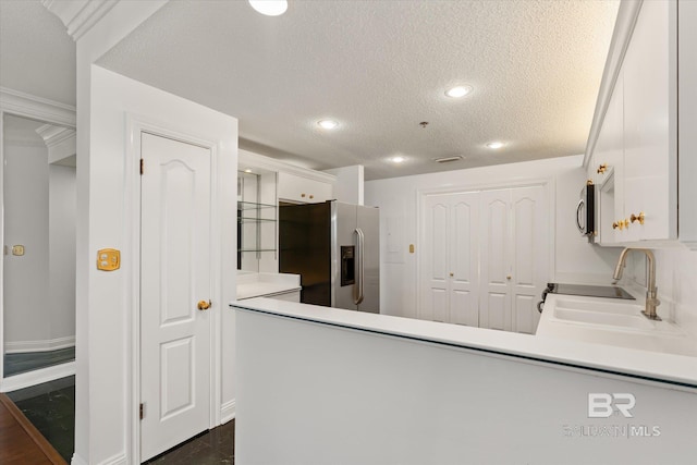 kitchen with appliances with stainless steel finishes, white cabinetry, a sink, a textured ceiling, and a peninsula