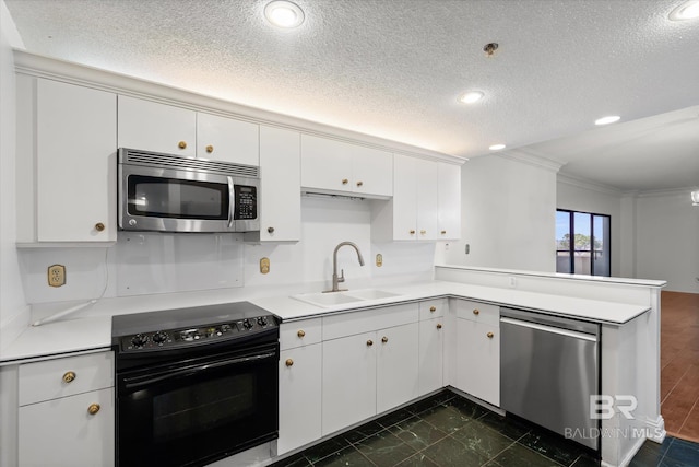 kitchen with a peninsula, appliances with stainless steel finishes, a sink, and light countertops