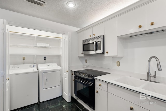 kitchen featuring a textured ceiling, black range with electric stovetop, a sink, stainless steel microwave, and washing machine and clothes dryer