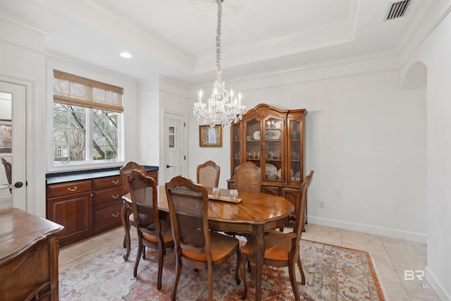 tiled dining area with crown molding, a tray ceiling, and an inviting chandelier