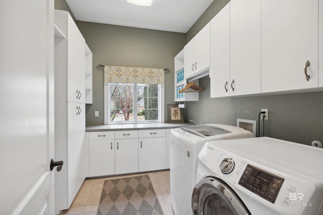 laundry area featuring cabinets, washer and dryer, and light tile patterned floors