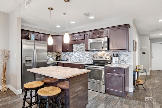 kitchen featuring a kitchen island, stainless steel appliances, dark brown cabinetry, and dark hardwood / wood-style floors