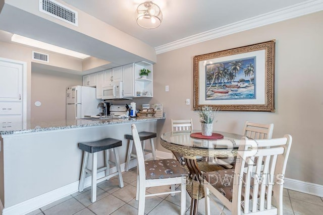 tiled dining room featuring sink and crown molding