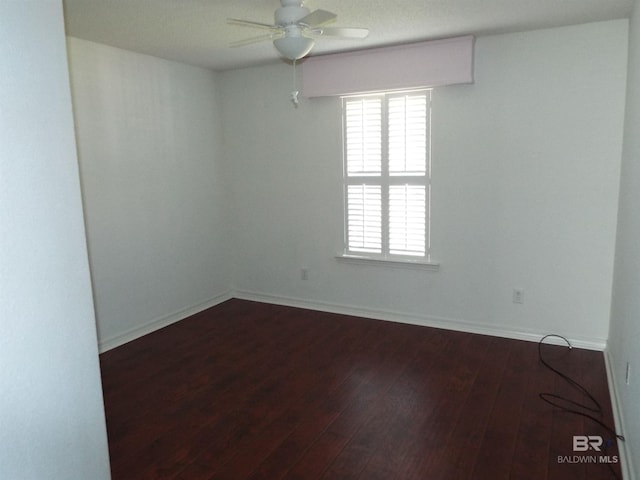 empty room featuring ceiling fan, baseboards, and dark wood-type flooring