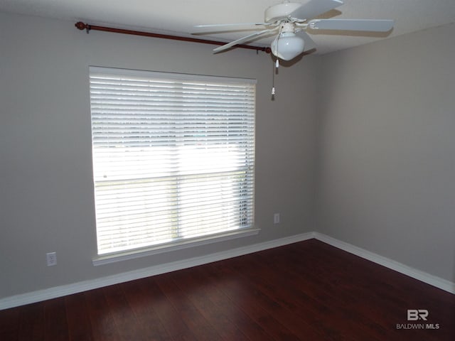 empty room featuring wood finished floors, a ceiling fan, and baseboards