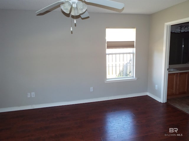 empty room with ceiling fan, baseboards, dark wood finished floors, and a sink