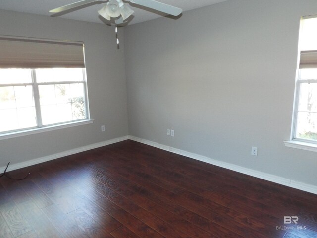 empty room with a ceiling fan, dark wood-style flooring, and baseboards