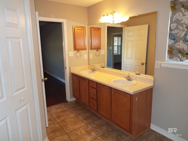 full bathroom with double vanity, tile patterned flooring, a sink, and baseboards