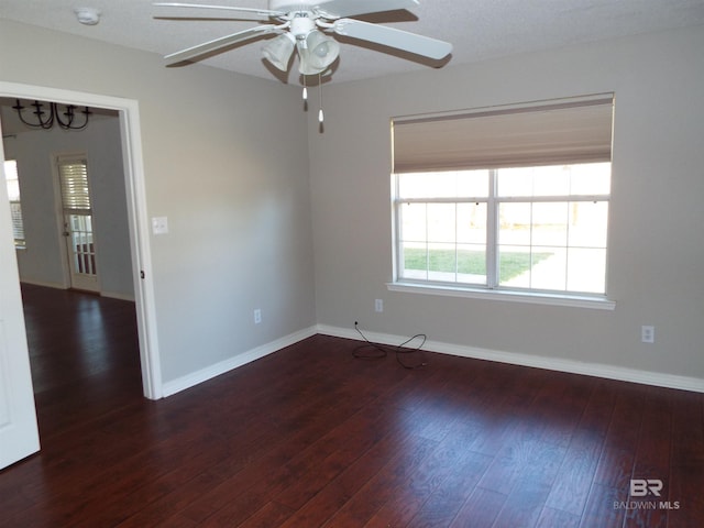 empty room with a ceiling fan, baseboards, and dark wood-style flooring