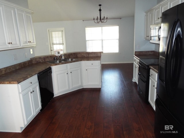 kitchen featuring dark wood finished floors, dark countertops, white cabinetry, a peninsula, and black appliances