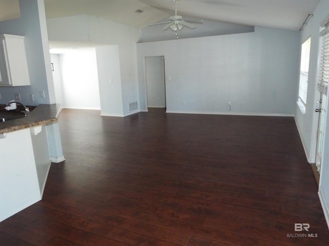 unfurnished living room with ceiling fan, a sink, visible vents, vaulted ceiling, and dark wood finished floors