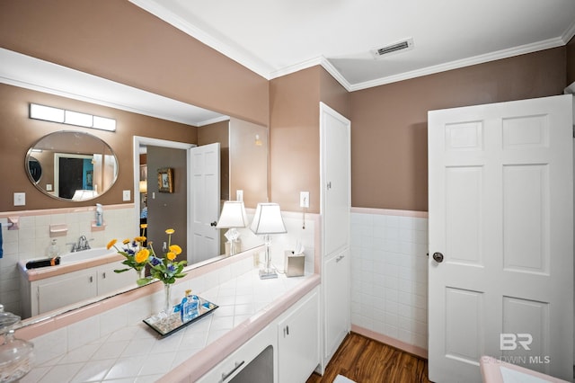 56 Old Bratt Rd, Atmore, AL 36502 - bathroom featuring tile walls, wood finished floors, crown molding, vanity, and wainscoting