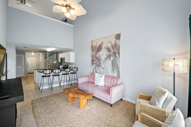 living room featuring ceiling fan, a towering ceiling, and light tile flooring