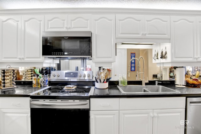 kitchen featuring a sink, appliances with stainless steel finishes, white cabinets, and dark countertops