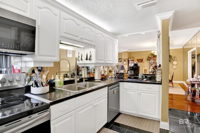 kitchen featuring visible vents, dark countertops, a sink, white cabinets, and stainless steel appliances