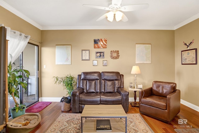 living area with baseboards, ornamental molding, ceiling fan, and wood finished floors