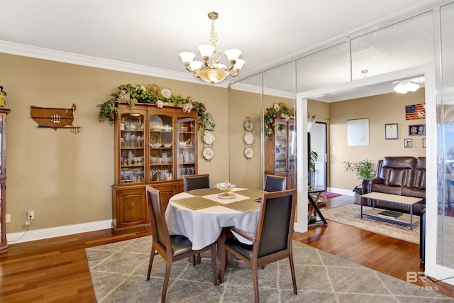 dining space with an inviting chandelier, ornamental molding, baseboards, and wood finished floors