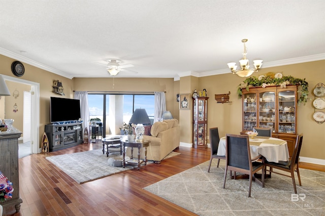 dining space with ornamental molding, ceiling fan with notable chandelier, and wood finished floors