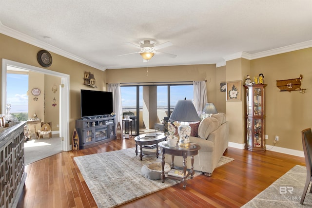 living area with crown molding, wood finished floors, baseboards, a textured ceiling, and a ceiling fan