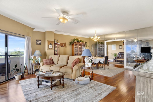 living area with crown molding, ceiling fan with notable chandelier, and wood finished floors