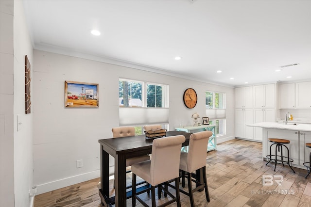 dining room featuring ornamental molding, sink, and light hardwood / wood-style flooring