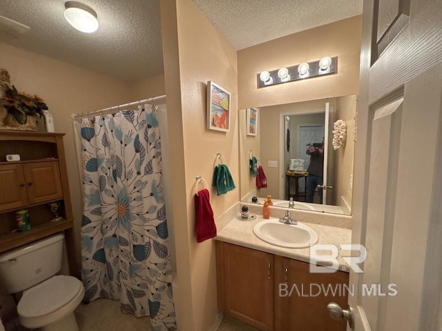 bathroom with a textured ceiling, toilet, vanity, and walk in shower