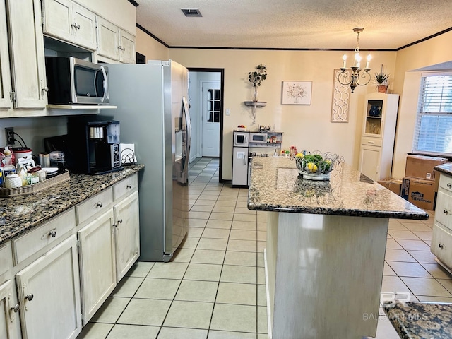 kitchen with crown molding, light tile patterned floors, stainless steel appliances, visible vents, and a textured ceiling