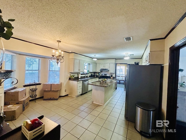 kitchen featuring stainless steel appliances, dark countertops, visible vents, ornamental molding, and under cabinet range hood