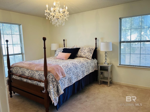 bedroom with a notable chandelier, carpet, baseboards, and a textured ceiling