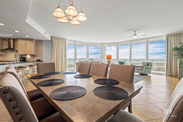 tiled dining room featuring ceiling fan with notable chandelier, expansive windows, a wealth of natural light, and sink