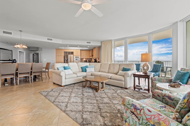 tiled living room with ceiling fan with notable chandelier