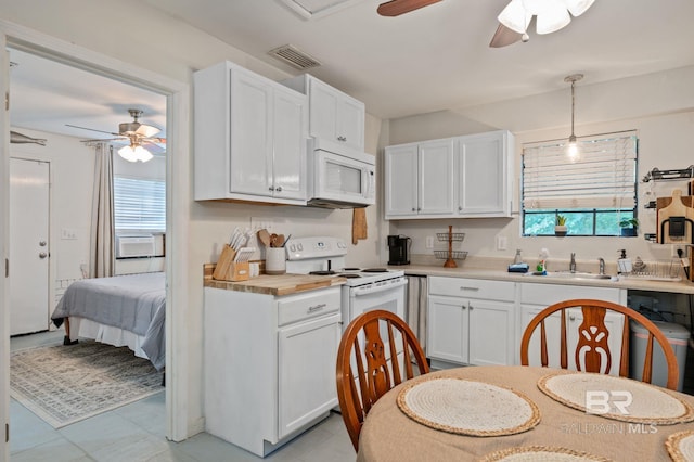 kitchen featuring visible vents, light countertops, white cabinets, white appliances, and a sink