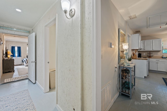 corridor with tile patterned floors, visible vents, and baseboards