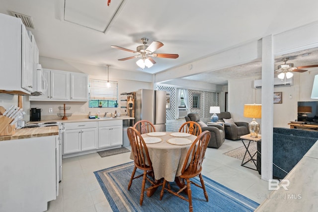 dining space with light tile patterned floors, visible vents, a wall mounted air conditioner, and ceiling fan