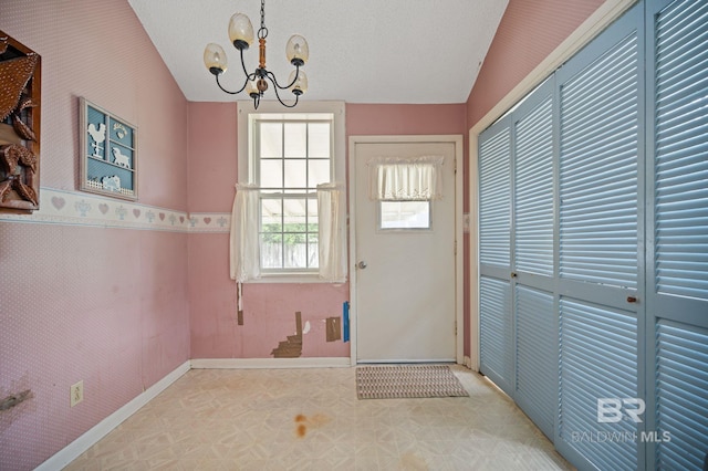 doorway featuring a notable chandelier, lofted ceiling, and a textured ceiling