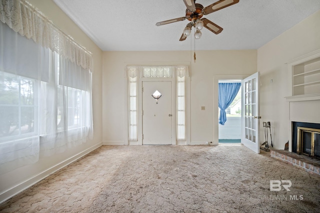 carpeted foyer entrance featuring a brick fireplace, a textured ceiling, and ceiling fan