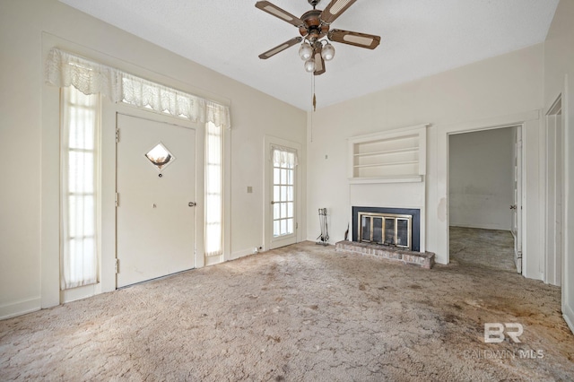 unfurnished living room featuring a fireplace, built in features, carpet flooring, and ceiling fan