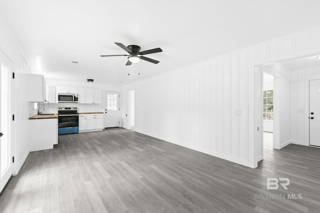 unfurnished living room featuring sink, wood-type flooring, and ceiling fan