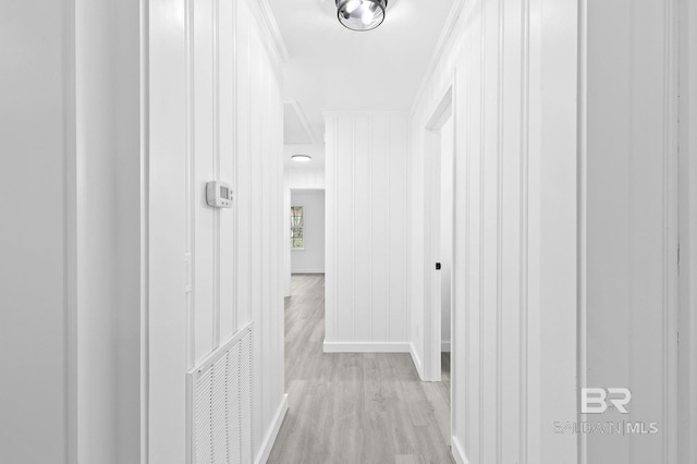 hall with light hardwood / wood-style floors and ornamental molding