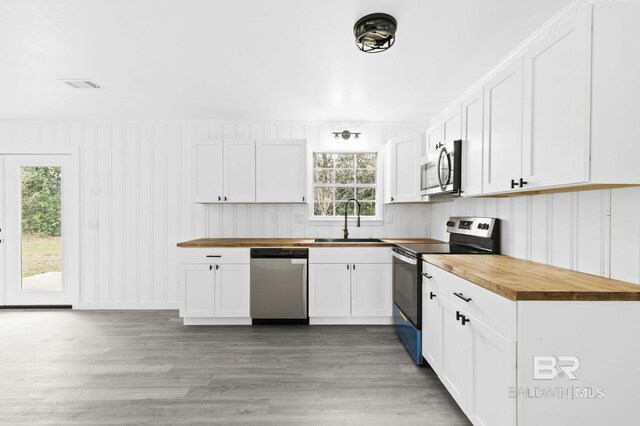 kitchen featuring sink, appliances with stainless steel finishes, butcher block countertops, and white cabinetry