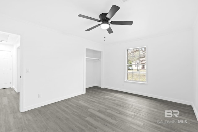 unfurnished bedroom with ceiling fan, crown molding, a closet, and hardwood / wood-style floors